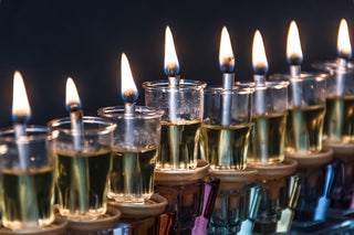 A traditional oil menorah with glowing flames, symbolizing the miracle of Chanukah, set against a warm background.